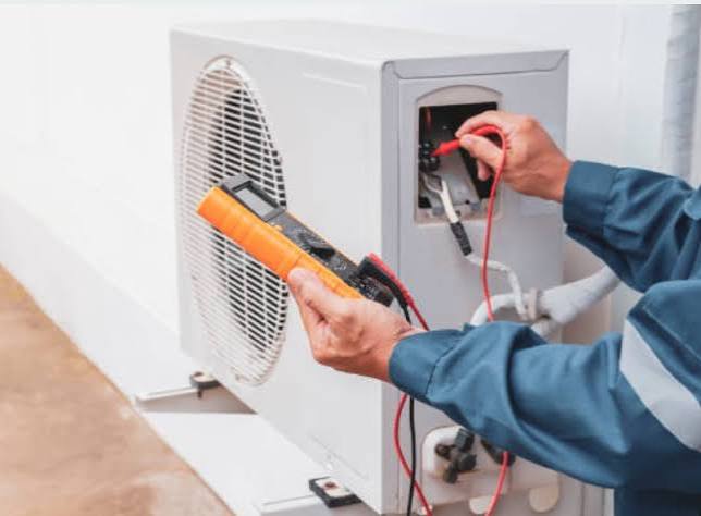 Technician using a multimeter to test an outdoor air conditioning unit